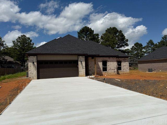 view of front of property featuring brick siding, a garage, and driveway