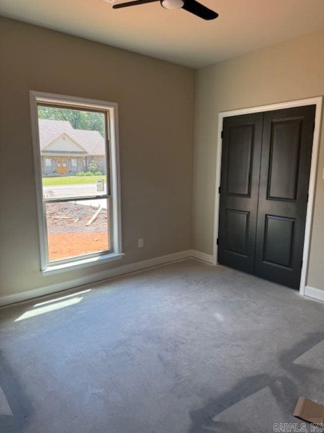carpeted spare room with a ceiling fan and baseboards