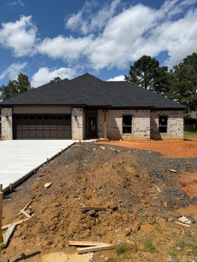view of front of house with brick siding, an attached garage, and driveway