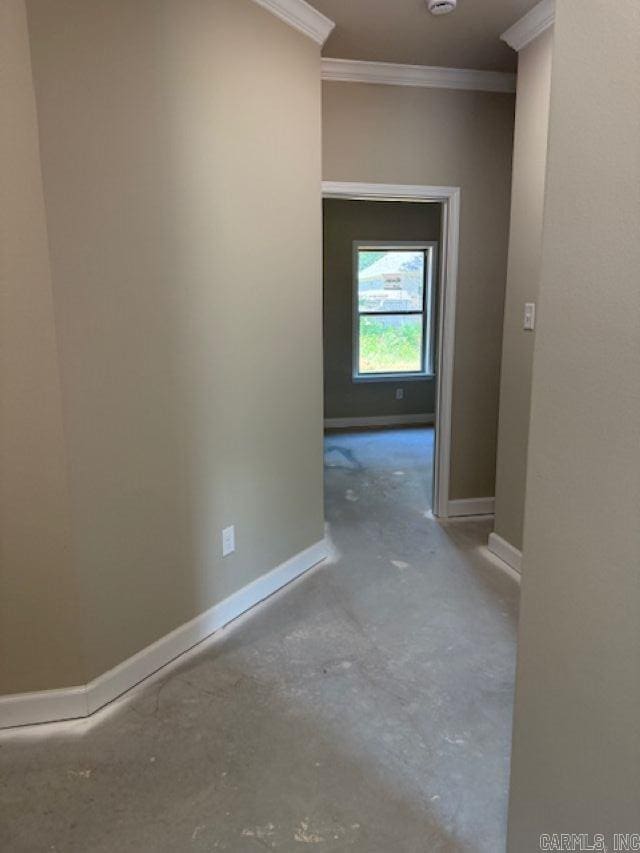 corridor with baseboards, ornamental molding, and concrete flooring