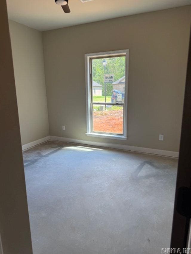 empty room featuring concrete flooring, baseboards, and a ceiling fan