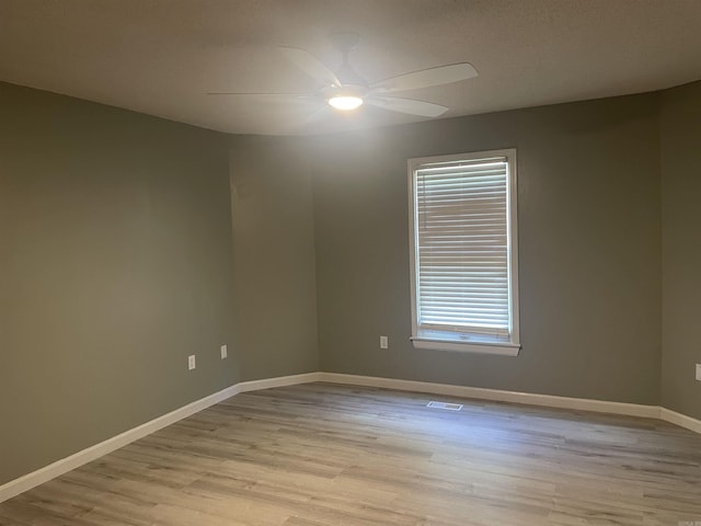 empty room featuring baseboards, light wood-style flooring, ceiling fan, and visible vents