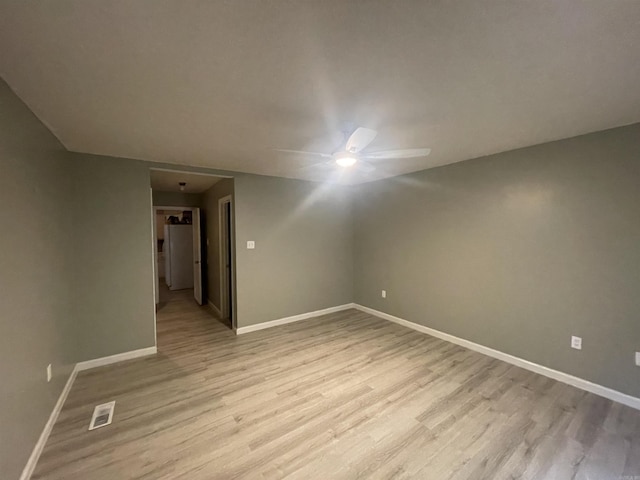 spare room featuring baseboards, visible vents, ceiling fan, and light wood finished floors
