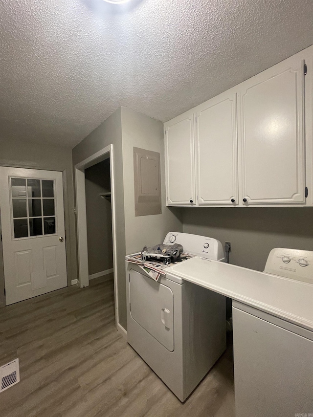laundry area with visible vents, light wood-type flooring, electric panel, cabinet space, and independent washer and dryer