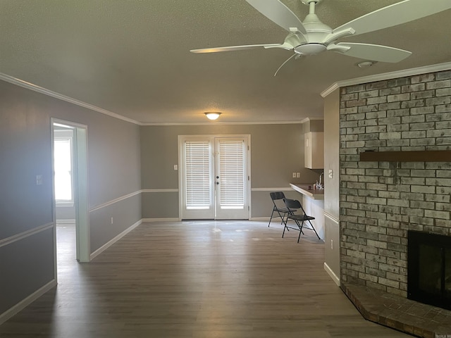 unfurnished dining area featuring ceiling fan, ornamental molding, french doors, and wood finished floors