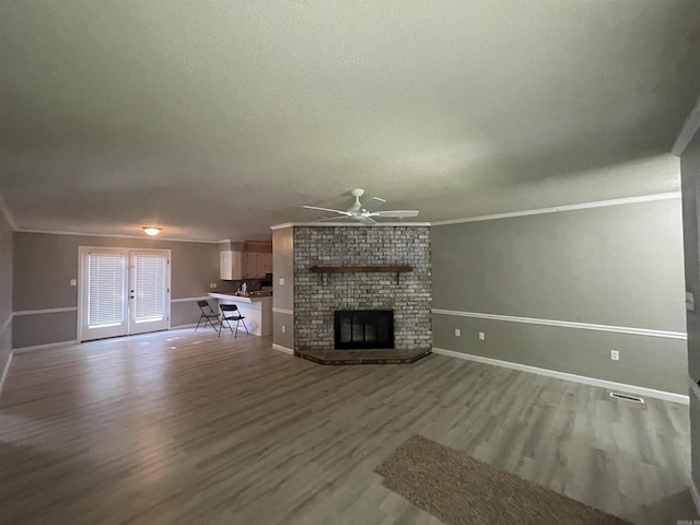 unfurnished living room featuring baseboards, a ceiling fan, wood finished floors, and ornamental molding
