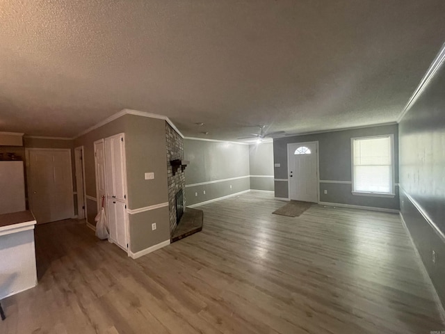 unfurnished living room with crown molding, a brick fireplace, and wood finished floors