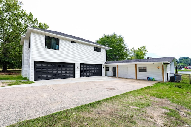 exterior space with a garage, fence, central AC unit, and concrete driveway