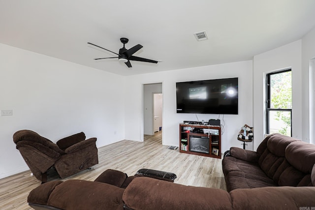 living room with ceiling fan, visible vents, baseboards, and light wood finished floors
