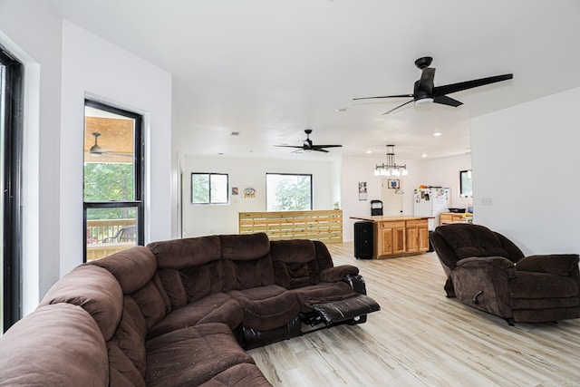 living area with recessed lighting, light wood-style flooring, ceiling fan with notable chandelier, and a wealth of natural light