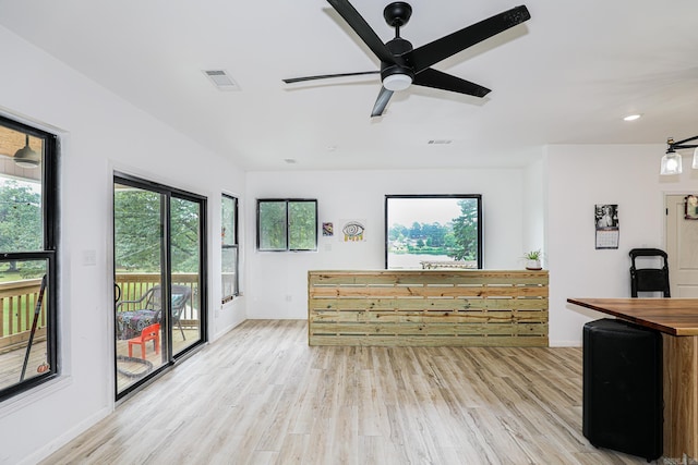 living room with light wood-style floors, baseboards, a ceiling fan, and visible vents