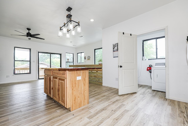 kitchen with a kitchen island, baseboards, washer / dryer, and light wood-style floors