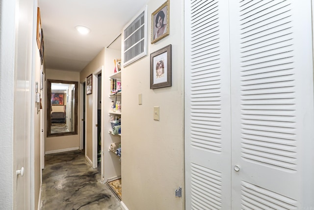 corridor featuring concrete flooring and baseboards