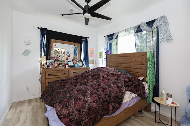bedroom with a ceiling fan, baseboards, visible vents, and wood finished floors