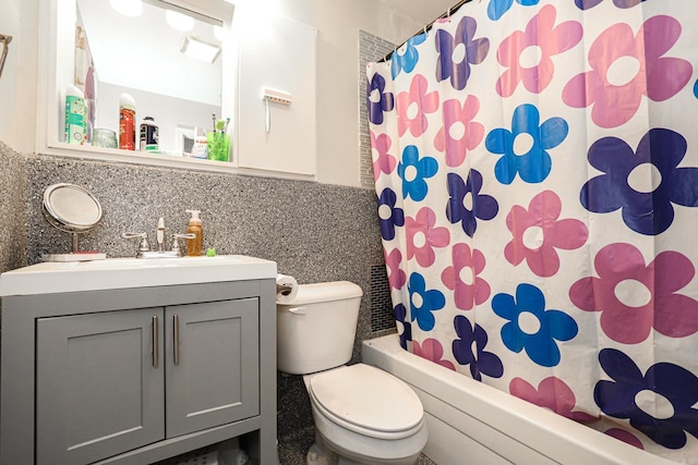 bathroom featuring vanity, shower / bath combo with shower curtain, toilet, and tile walls