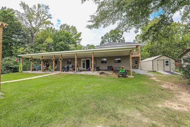 back of property with a yard, a storage shed, an outdoor structure, and a patio area