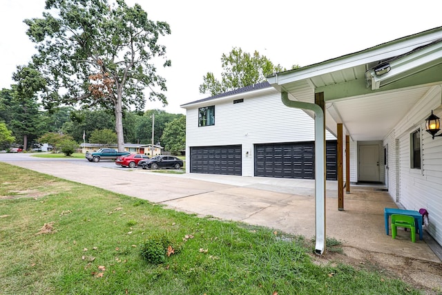 view of side of property with concrete driveway and a lawn