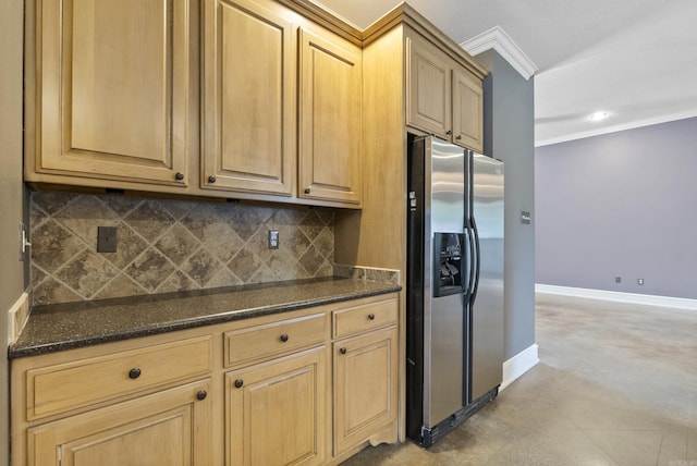 kitchen featuring ornamental molding, baseboards, stainless steel refrigerator with ice dispenser, dark stone counters, and tasteful backsplash