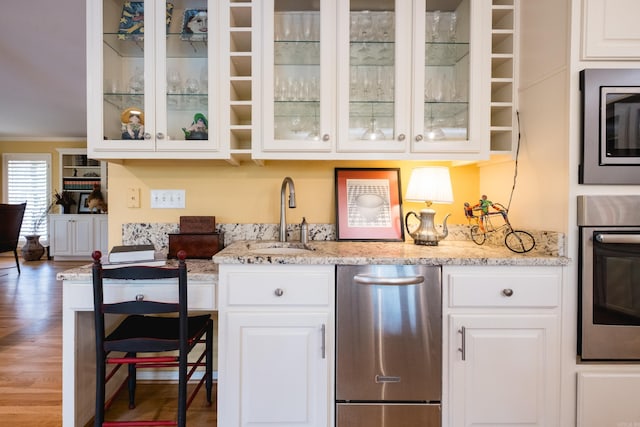 bar with a sink, appliances with stainless steel finishes, and wood finished floors