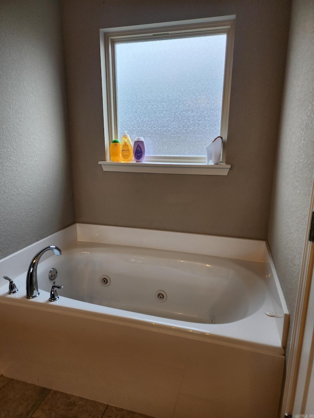 bathroom with tile patterned flooring, a textured wall, and a whirlpool tub