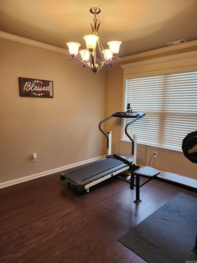 exercise room featuring visible vents, crown molding, wood finished floors, baseboards, and a chandelier