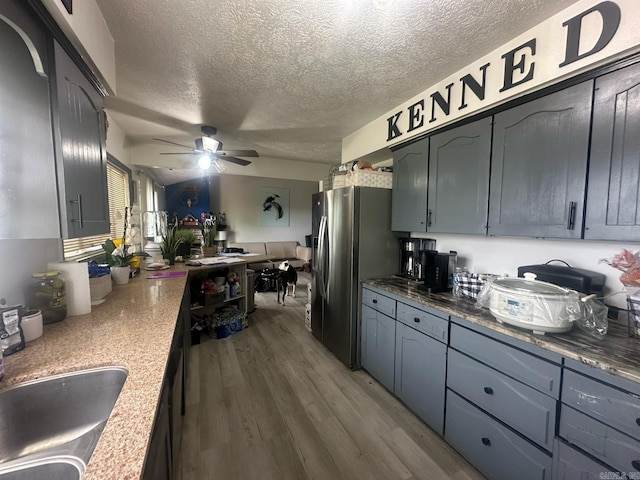 kitchen featuring a ceiling fan, stainless steel refrigerator with ice dispenser, a textured ceiling, dark wood finished floors, and a sink