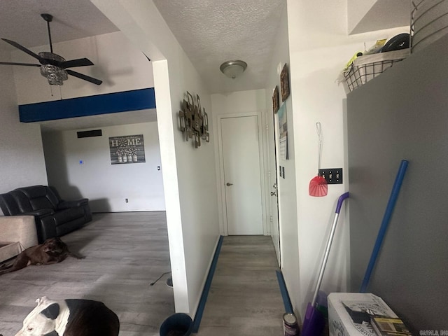 corridor with a textured ceiling, baseboards, and wood finished floors