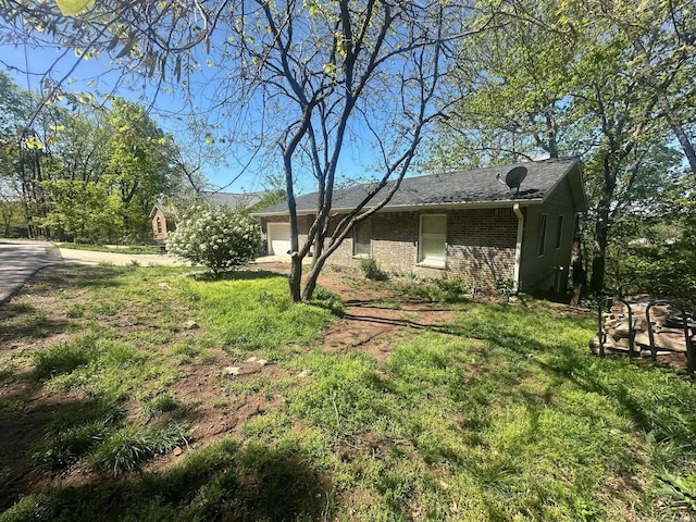 view of side of home with a lawn, an attached garage, and brick siding