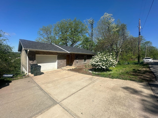ranch-style house featuring a garage, a shingled roof, concrete driveway, and brick siding