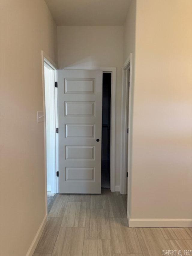 hallway featuring baseboards and light wood-type flooring