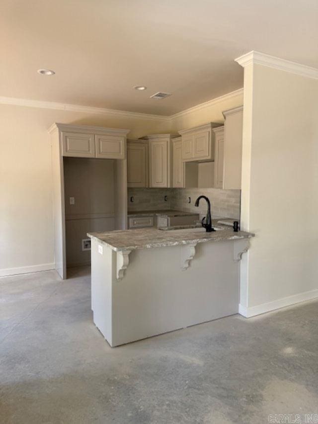 kitchen with a breakfast bar area, baseboards, concrete floors, and ornamental molding