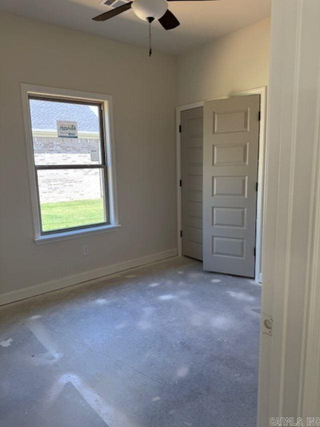 spare room featuring ceiling fan, concrete floors, and baseboards