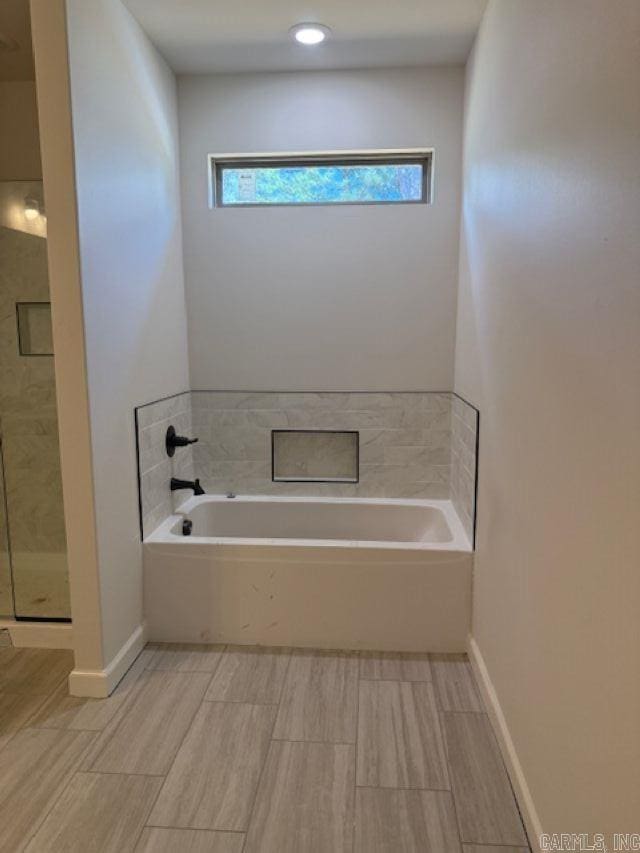 full bathroom with baseboards, a garden tub, a stall shower, and wood finish floors