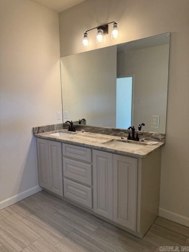 full bath with a sink, baseboards, and double vanity