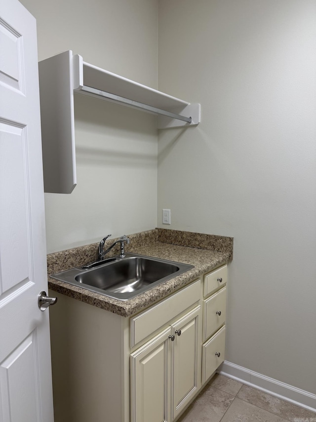 laundry area with a sink, baseboards, and light tile patterned floors