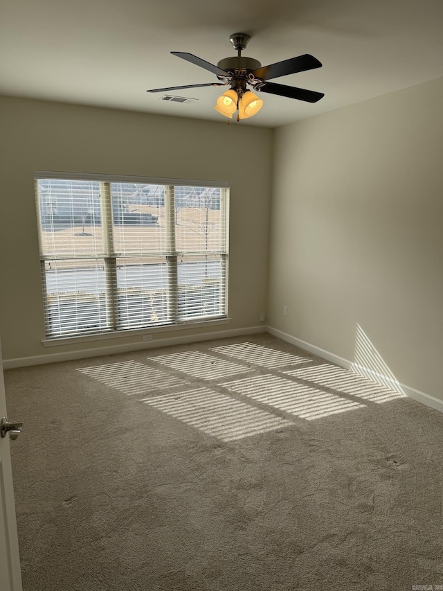 empty room with a ceiling fan, baseboards, visible vents, and carpet