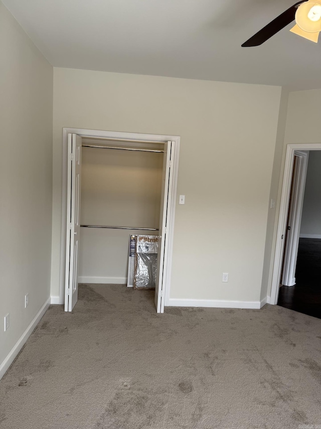 unfurnished bedroom with carpet floors, a ceiling fan, baseboards, and a closet