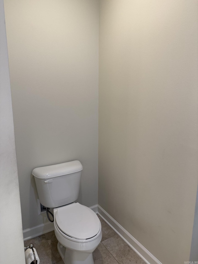 bathroom featuring baseboards, tile patterned floors, and toilet