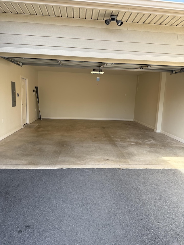 garage with baseboards and electric panel