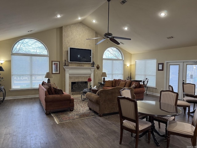 living area with a fireplace, high vaulted ceiling, a ceiling fan, wood finished floors, and visible vents