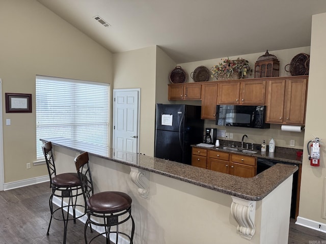 kitchen featuring visible vents, dark wood finished floors, brown cabinets, a sink, and black appliances