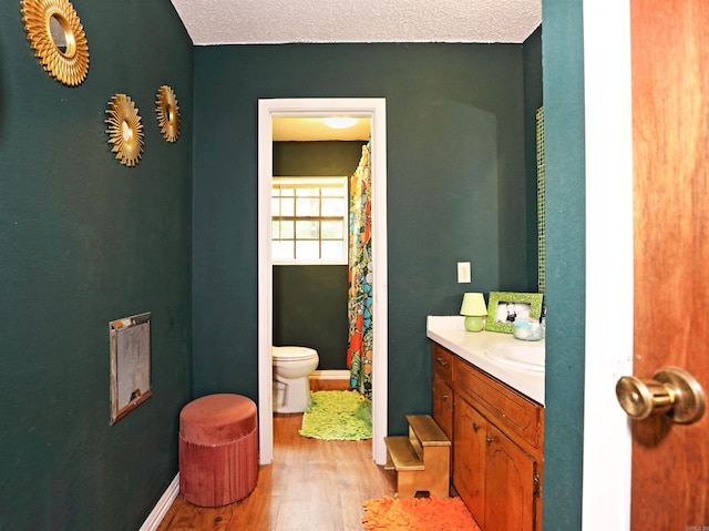 bathroom with toilet, baseboards, wood finished floors, and vanity