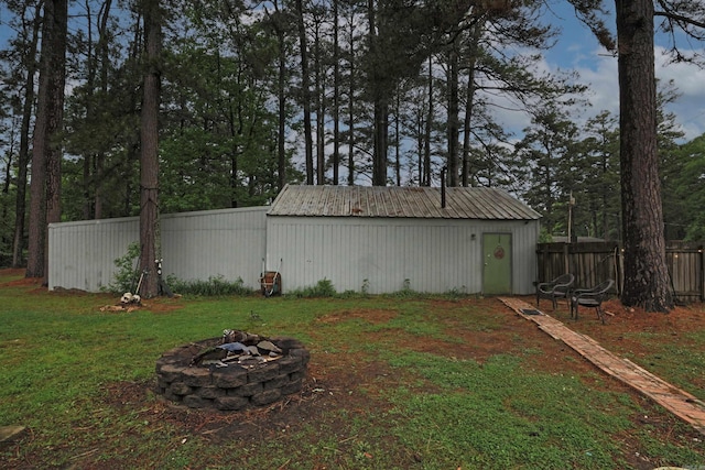 view of yard featuring a pole building, fence, a fire pit, and an outbuilding