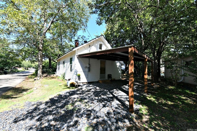 view of side of property with gravel driveway and an attached carport