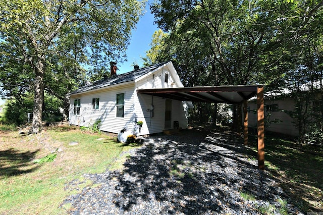 view of side of property featuring driveway, a chimney, and an attached carport