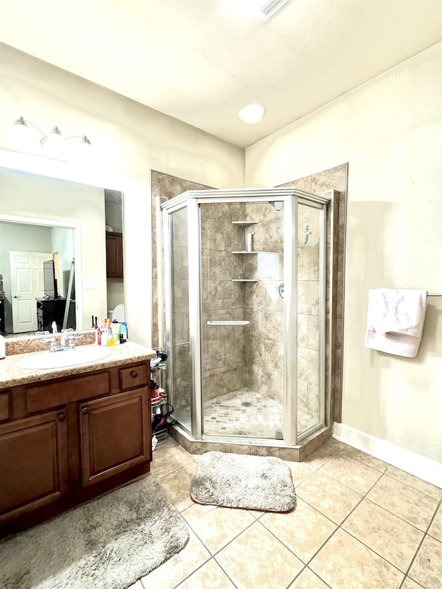 bathroom featuring vanity, tile patterned floors, baseboards, and a stall shower