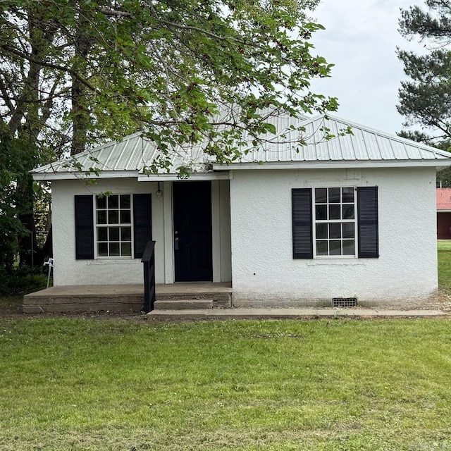 single story home with stucco siding, metal roof, and a front lawn