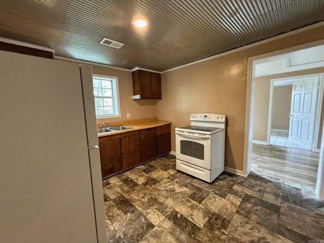 kitchen featuring a sink, white appliances, light countertops, stone finish flooring, and visible vents