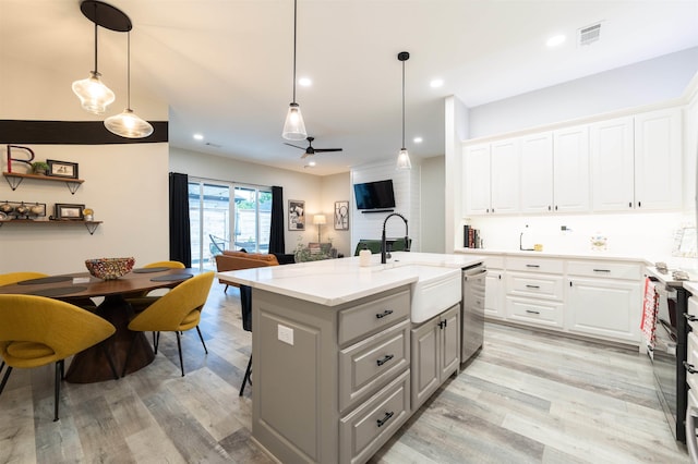 kitchen featuring visible vents, a sink, dishwasher, and light wood-type flooring