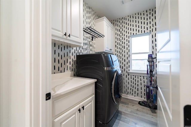 laundry area with cabinet space, wallpapered walls, baseboards, light wood-type flooring, and washer and clothes dryer